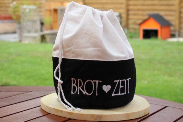 Schwarzer Brotbeutel mit weißem Kordelzug und Aufdruck „Brot Zeit“ – geschlossen