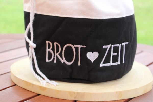 Aufschrift „Brot Zeit“ in schwarz auf weißem Baumwollstoff – Detailansicht