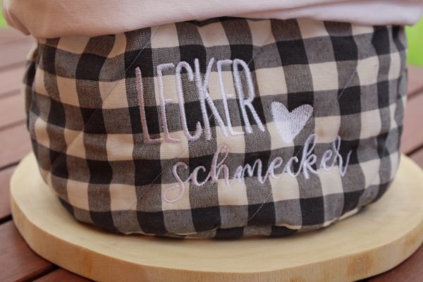 Schriftzug „Lecker Schmecker“ in Schwarz auf graukariertem Stoff – Detail