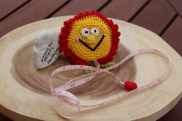 Rollmaßband in gehäkelter Blume – rot-gelb – seitlich mit Band sichtbar