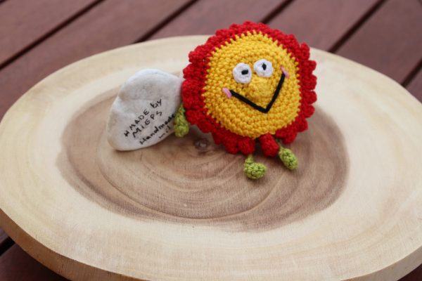 Gehäkelte Blume in Rot und Gelb als Hülle für Rollmaßband – Draufsicht