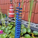 Blauer Windspinner am Gartenteich mit Leuchtturm