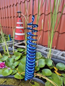 Blauer Windspinner am Gartenteich mit Leuchtturm